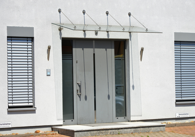 Moderne Haustür mit Seitenteilen und Zugstangen-Vordach aus Glas